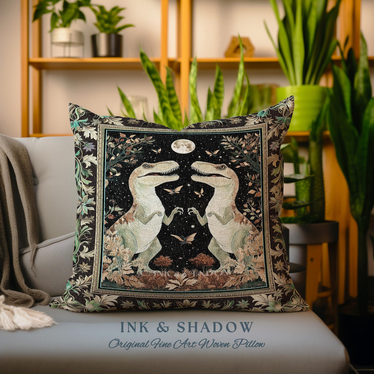 May include: A black and brown woven pillow with a tapestry design featuring two dinosaurs facing each other under a full moon. The dinosaurs are green and white with intricate details. The background is a dark forest scene with butterflies and stars. The pillow has the text "INK & SHADOW Original Fine Art Woven Pillow" at the bottom.