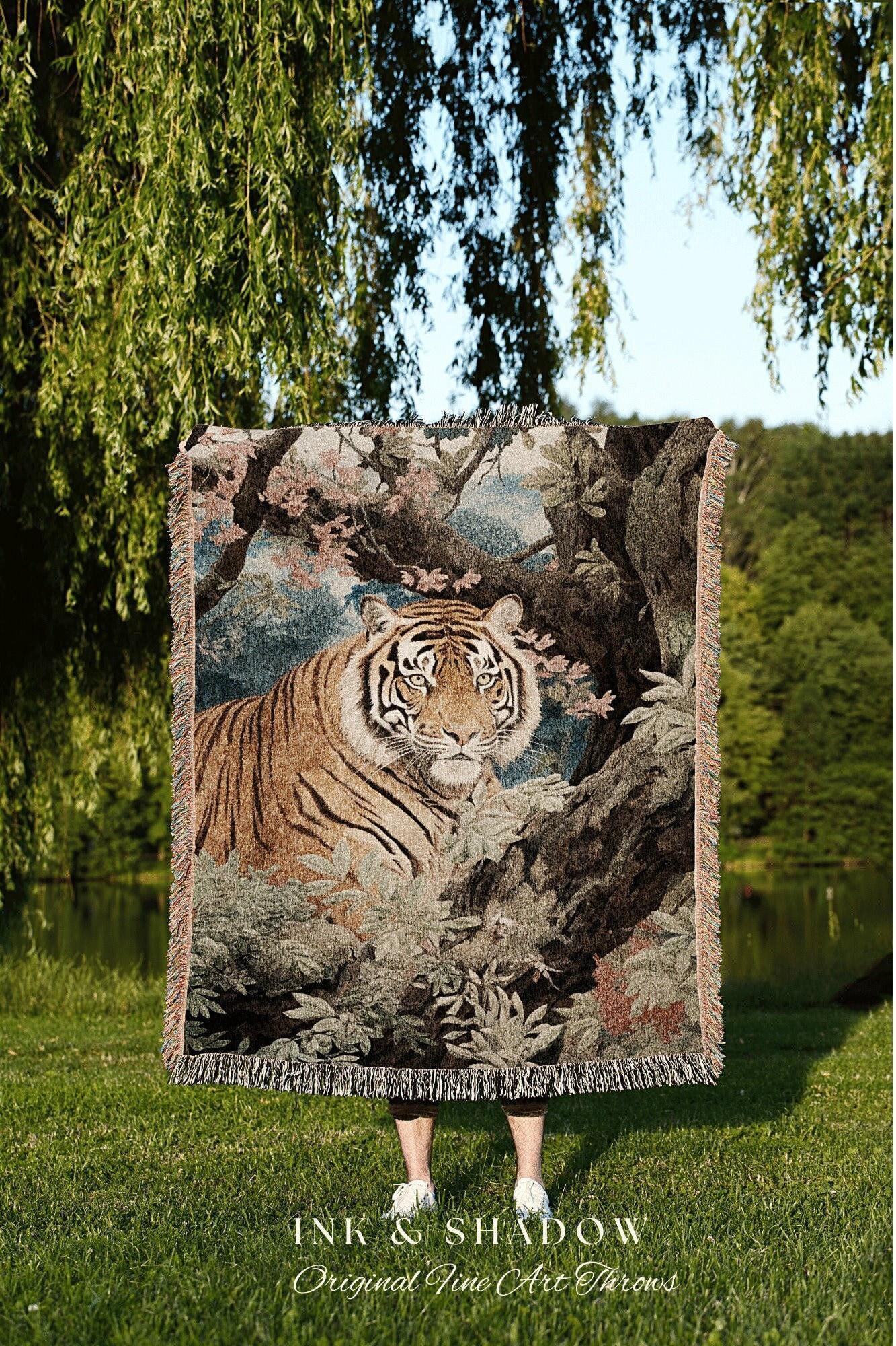 May include: A woven tapestry throw blanket featuring a detailed image of a tiger in a forest setting. The blanket has a fringed edge and is predominantly brown, green, and blue. The text "INK & SHADOW Original Fine Art Throws" is visible at the bottom.