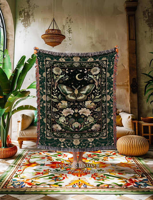 May include: Dark green throw blanket with a central butterfly design, surrounded by floral and celestial motifs. The blanket has a fringed edge and is displayed against a textured wall. The blanket is a decorative home textile.