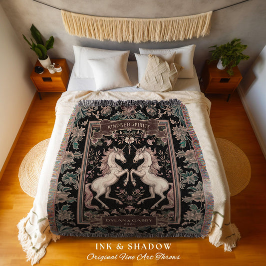 May include: A black throw blanket with a design featuring two white unicorns facing each other. The blanket has a floral border with the words "KINDRED SPIRITS" and "DYLAN & GABBY 2024". The blanket is fringed and has the text "INK & SHADOW Original Fine Art Throws".