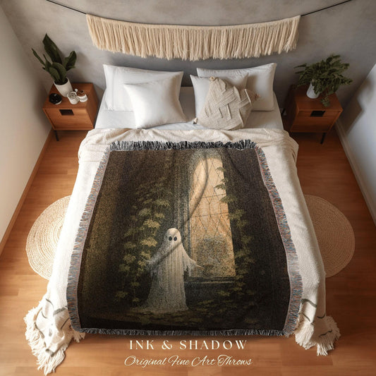May include: A woven throw blanket featuring a ghostly figure in a window, surrounded by foliage. The blanket has a dark, moody color palette with fringe edges. Text at the bottom reads "INK & SHADOW Original Fine Art Throws."