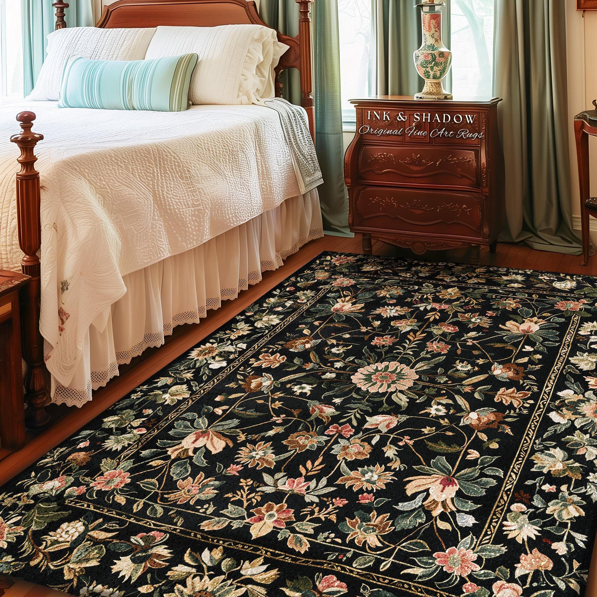 May include: A black rectangular rug with a floral pattern in shades of pink, green, and cream. The rug is placed in a bedroom setting, with a bed and nightstand visible. The text "INK & SHADOW Original Fine Art Rugs" is on the nightstand.