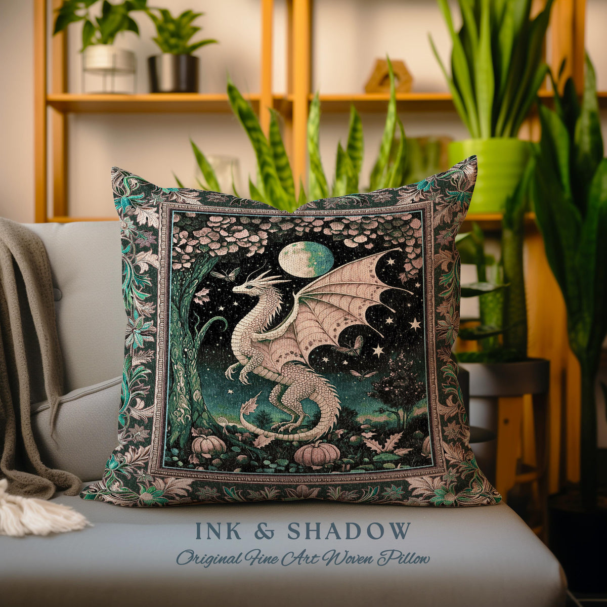 May include: A decorative pillow featuring a woven tapestry design of a white dragon with outstretched wings in a forest setting. The dragon is surrounded by stars, a crescent moon, and a tree. The pillow has a dark green background with accents of pink, blue, and gold. The text "INK & SHADOW Original Fine Art Woven Pillow" is printed on the bottom of the pillow.
