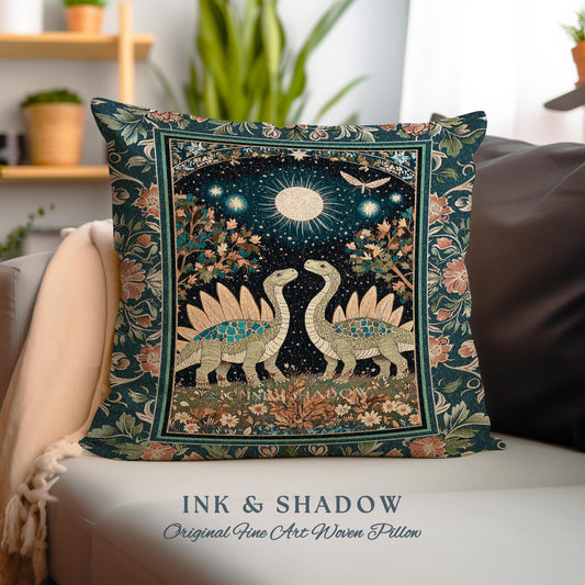 May include: A woven pillow with a dark green background and a floral pattern. The center of the pillow features a scene of two dinosaurs with a full moon and stars in the background. The text "INK & SHADOW Original Fine Art Woven Pillow" is printed below the image.