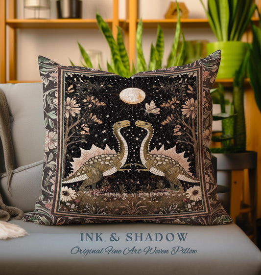 May include: A decorative pillow with a woven tapestry design featuring two dinosaurs facing each other under a full moon. The background is a dark blue with stars and floral accents. The text "INK & SHADOW Original Fine Art Woven Pillow" is printed below the image.