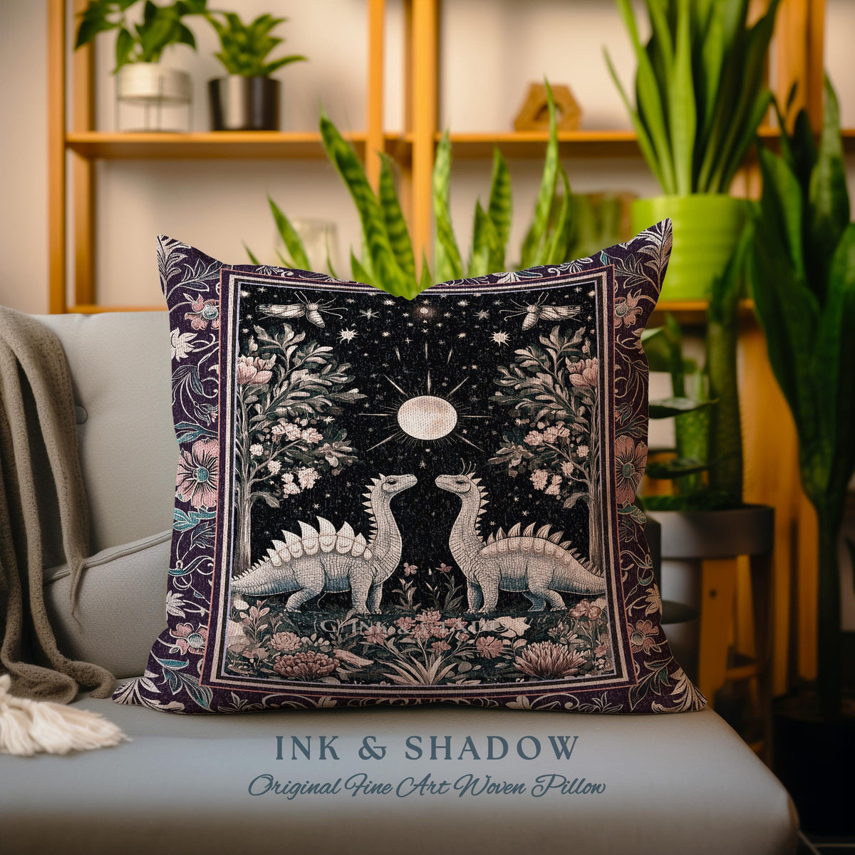 May include: A purple and pink woven pillow with a design of two dinosaurs standing under a full moon in a forest. The pillow has the text "INK & SHADOW Original Fine Art Woven Pillow" at the bottom.