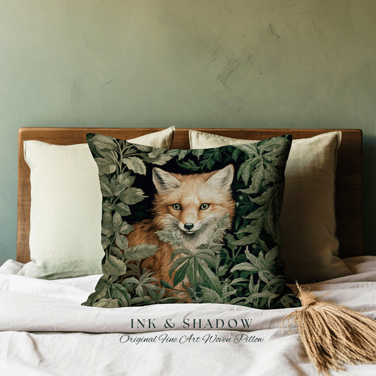 May include: A decorative pillow with a woven design of a fox peeking out from behind green leaves. The pillow is labeled "INK & SHADOW Original Fine Art Woven Pillow".