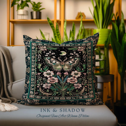May include: A dark green throw pillow with a black background featuring a detailed illustration of a moth with pink flowers and leaves. The pillow has a gold border and the text "INK & SHADOW Original Fine Art Woven Pillow" at the bottom.