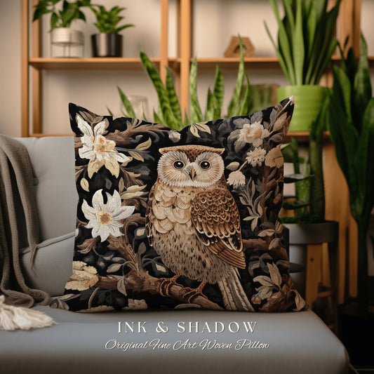 May include: A decorative pillow with a woven design of an owl perched on a branch surrounded by flowers. The pillow is black with brown, white, and beige accents. The text "INK & SHADOW Original Fine Art Woven Pillow" is printed on the bottom of the pillow.