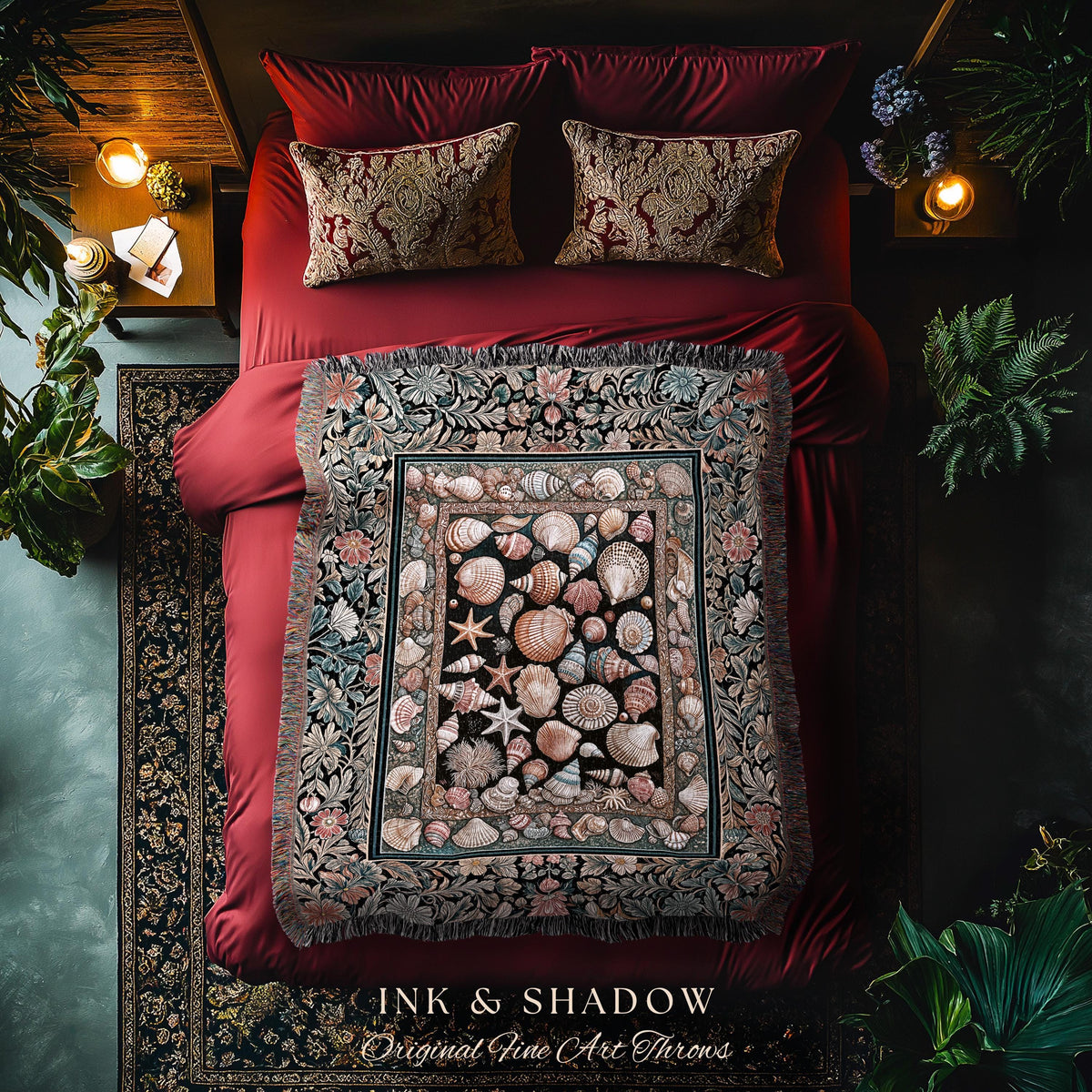 May include: A bed with red bedding, two patterned pillows, and a decorative throw blanket. The throw features a seashell design in the center, framed by floral patterns. The text "INK & SHADOW Original Fine Art Throws" is at the bottom.