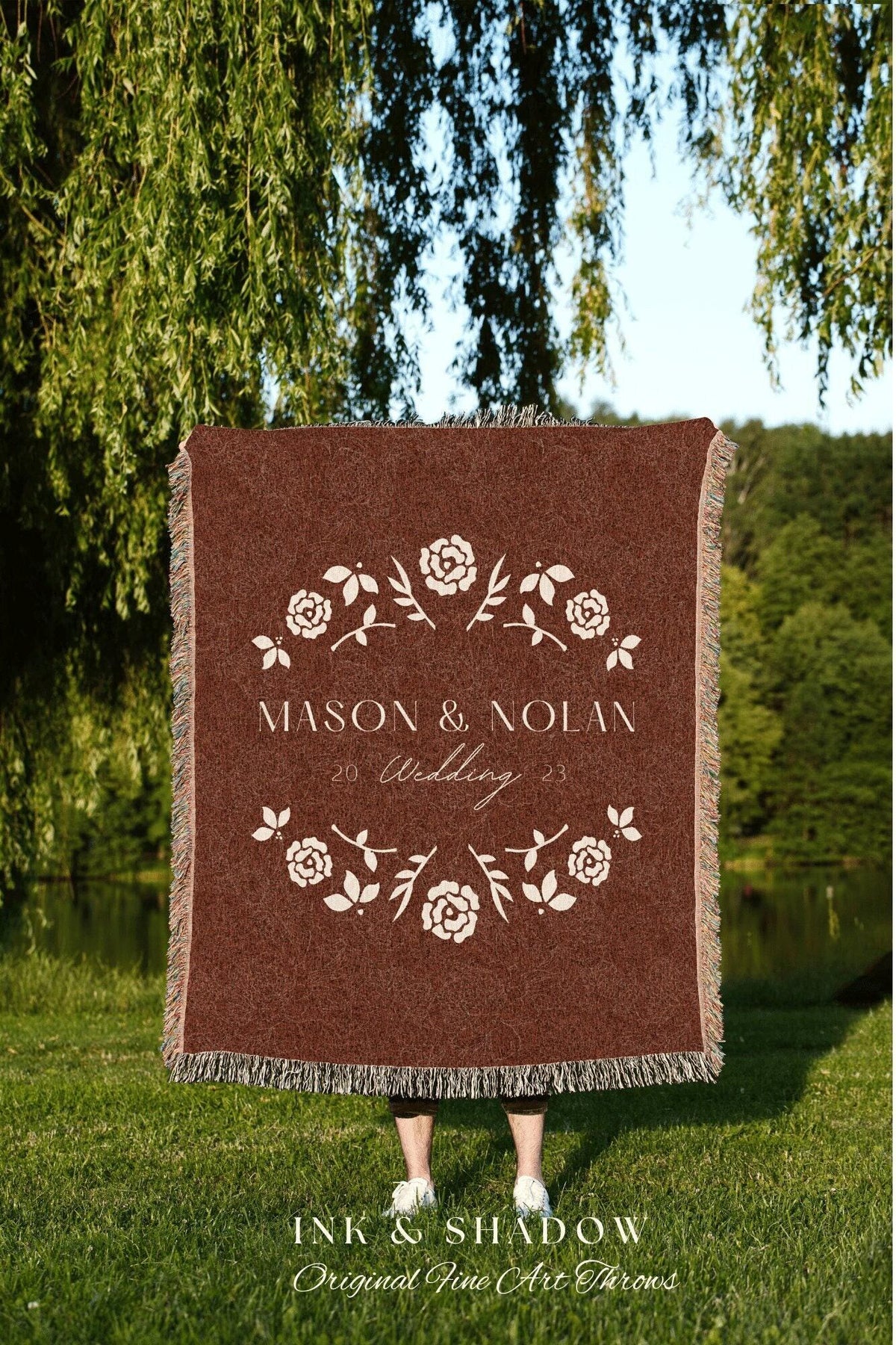 May include: A woven tapestry throw blanket with a maroon background and a white floral design. The text 'MASON & NOLAN 20 Wedding 23' is in the center of the blanket. The text 'INK & SHADOW Original Fine Art Throws' is below the blanket.