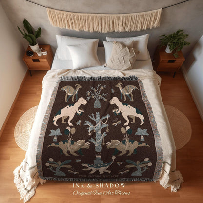 May include: A brown throw blanket with a dinosaur design. The blanket features various dinosaur illustrations in beige and gray, with a fringe border. The text "INK & SHADOW Original Fine Art Throws" is at the bottom.